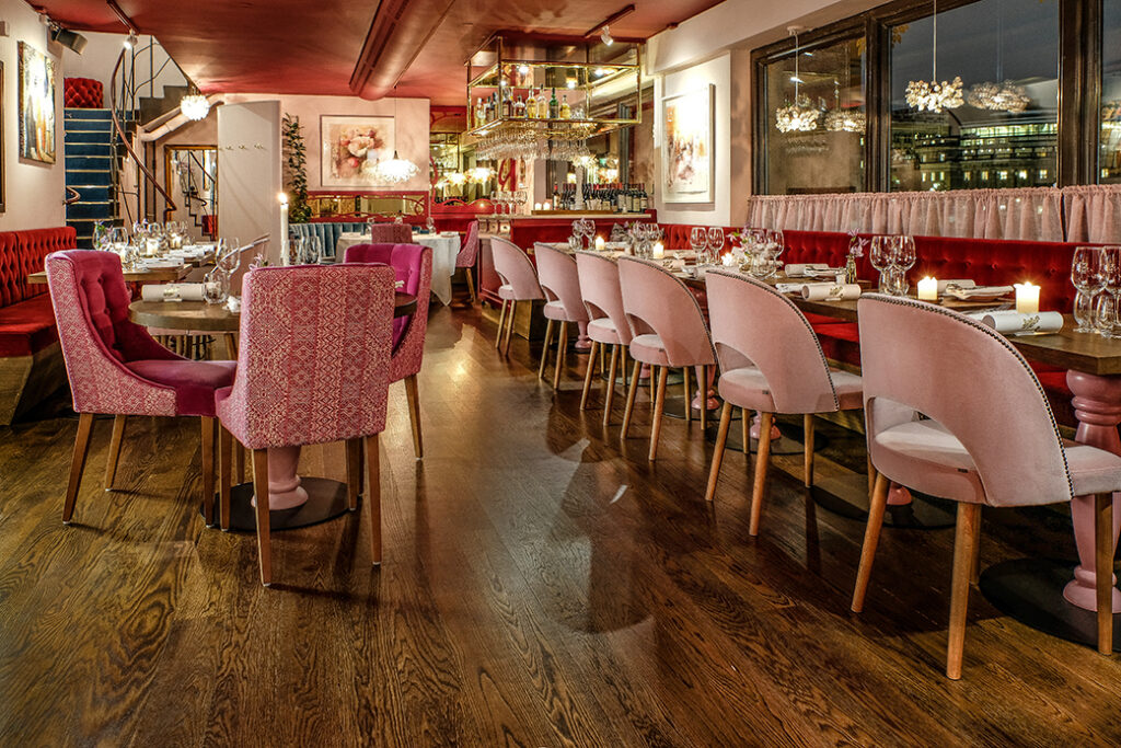 Restaurangmatsal med rosa stolar och dukade bord