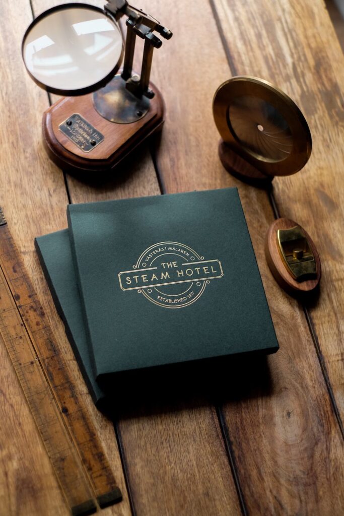 Presentkartong för The Steam Hotel med logotyp i guldfolie